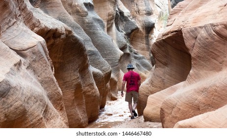 Man Walking Through Dramatically Curved Utah Slot Canyon