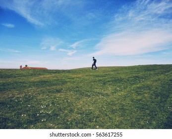 A man walking through a wast fields on a sunny day with blue sky 