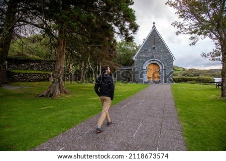 A man walking  towards a church at Gougane Barra National Park, Ireland