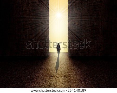 Man walking towards the light from darkness