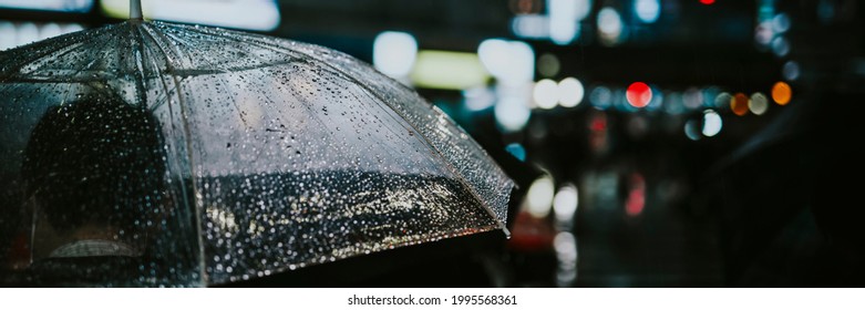 Man Walking With A Transparent Umbrella In A City At Night