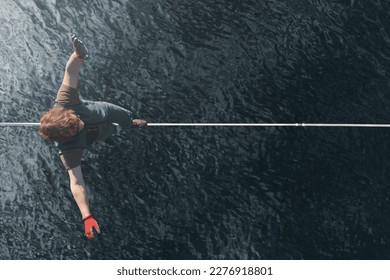 A man walks along a highline over water without insurance. Top view. Extreme activity and lifestyle