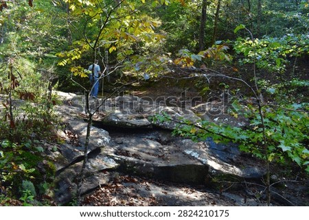 A man walks along the solid rock creek bed above the Glory Hole, a unique waterfall near Ozone, Arkansas, AR, United States, USA.