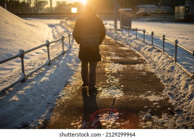 Man Walks Down Road Into Sunset. Sun Is Setting. Pedestrian In Winter. Man In Sun. Glare From Bright Rays. Atmospheric Photo.