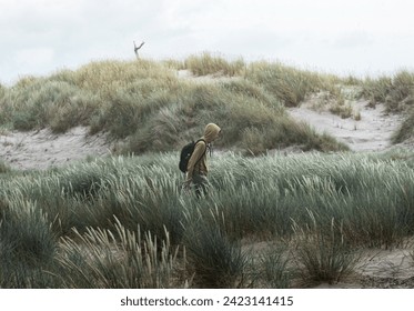 man walks in the dunes on a sandy beach in Denmark - Powered by Shutterstock