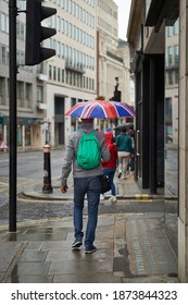 A Man Walks In The London Rain With An Umbrella Stamped With The British Flag