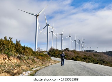 A Man Walks On The Access Road To A Wind Farm In The Mountains