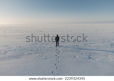 A man walks on the frozen and snow-covered surface of the sea. arctic region