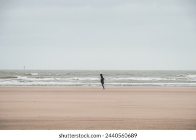 Man walks on a sandy beach in the face of high winds near Blankenberge, west coast of Belgium. Exploring and discovering Belgium. - Powered by Shutterstock