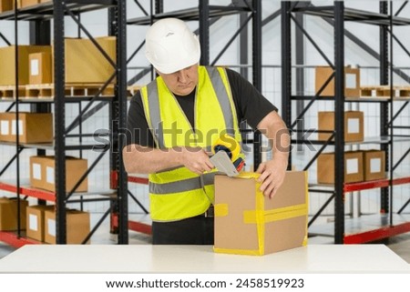 Man warehouse packer. Worker with box and tape dispenser. Packer near racks for boxes. Warehouse contractor wearing reflective vest. Warehouse packer career. Man storekeeper in white hardhat