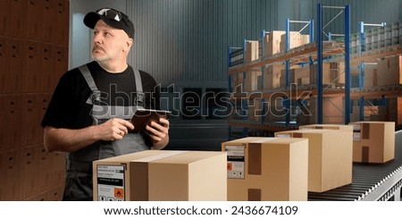 Man warehouse specialist. Storekeeper male near conveyor with boxes. Man controls packing of parcels. Warehouseman uses tablet for warehouse work. Warehouse manager in hangar with shelving