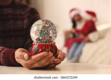 Man in warm Christmas sweater with snow globe at table, closeup - Powered by Shutterstock