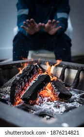 Man Warming Up By A Campfire. Person Warming Their Hands By The Fire In The Cold. Relaxing By The Burning Cozy Fire Pit And Trying To Stay Warm Closeup