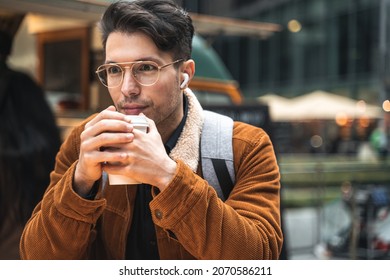 Man warming with cup of coffee while relaxing at the street cafe during the autumn day
