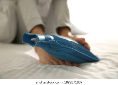 Man Warming Feet With Hot Water Bottle On Bed, Closeup