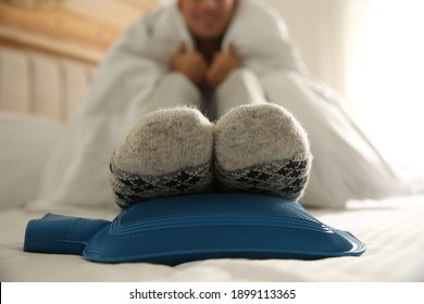 Man Warming Feet With Hot Water Bottle On Bed, Closeup