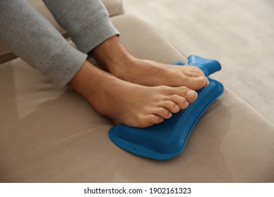 Man Warming Feet With Hot Water Bottle On Sofa, Closeup