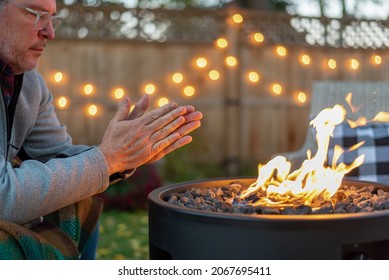 Man warming his hands by a fire at dusk