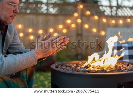 Man warming his hands by a fire at dusk