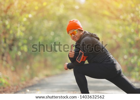 The man warms up muscles before jogging in forest with sunlight path in late summer or fall. fitness healthy lifestyle concept.