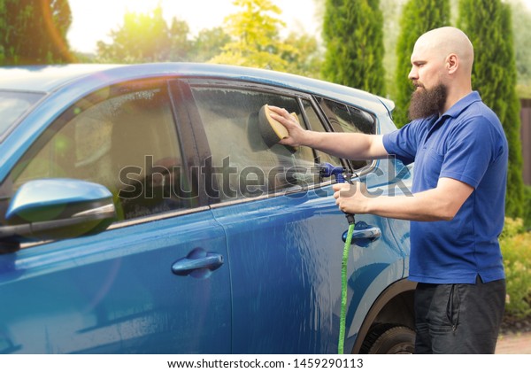 A man washes a car with a\
hose.