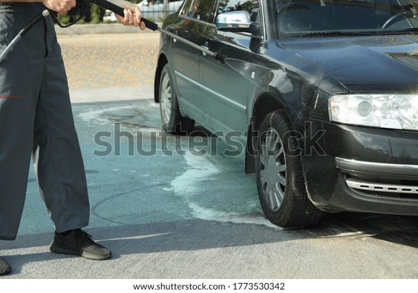 A man\
washes a car in a manual car wash. Clear\
car