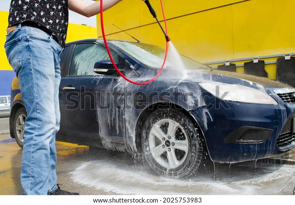 a man washes a car at a car wash with water\
pressure. self-service car\
wash