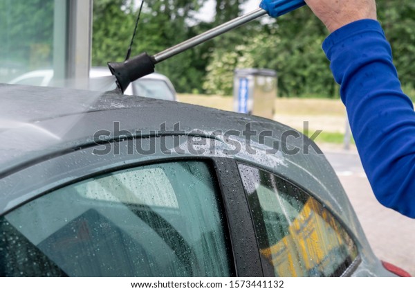 A man washes a car with a washing gun. Contact\
less car wash with active foams and a water jet under high\
pressure. Washing the auto outdoor.\

