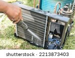 A man washes and cleans the evaporator coil of an old window type air conditioning unit with a high pressure hose