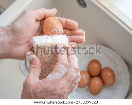 Man washes eggs with a sponge under running water in a kitchen sink. Symbolizes food safety, healthy eating, and kitchen hygiene. Ideal for cooking, nutrition, and culinary content. Safe food handling