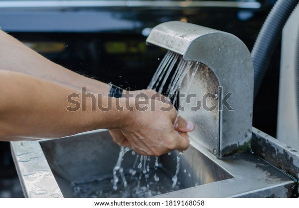 man washes his hands in a washbasin at a\
self-service car wash