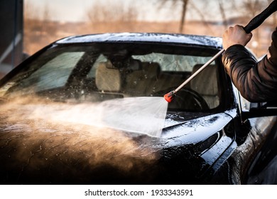 A Man Washes His Luxury Black Sports Car In A Manual Car Wash.