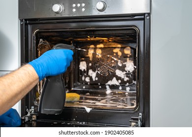 A Man Washes The Oven With Foam And A Spray Bottle. House Cleaning