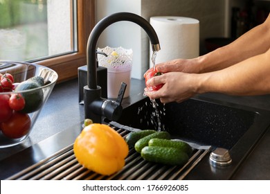 A man washes vegetables in the kitchen sink. - Powered by Shutterstock