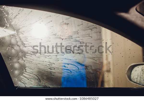 man\
washing automobile manual car washing self service,cleaning with\
foam,pressured water. Washing car in self service station with high\
pressure blaster window viewed from inside\
car