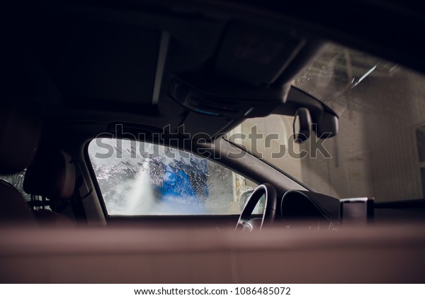 man
washing automobile manual car washing self service,cleaning with
foam,pressured water. Washing car in self service station with high
pressure blaster window viewed from inside
car