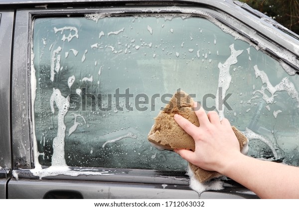 Man washing a car. Hand with foam sponge.\
Clouse up washing a car. Cleaning a\
car.