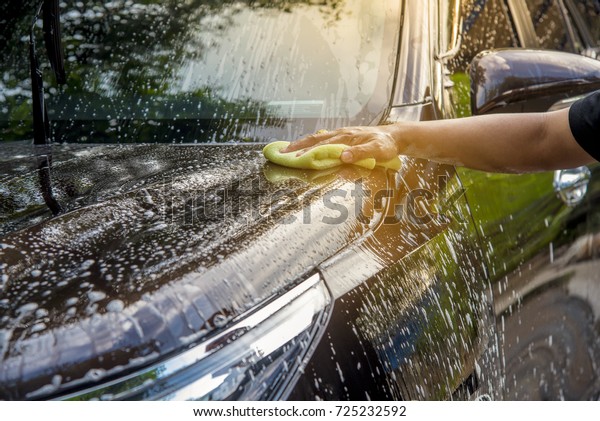 Man is washing a car in\
his holiday. 