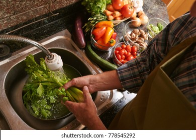 Man washing celery in the kitchen sink, view from above - Powered by Shutterstock