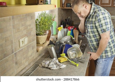 Man Washing Dirty Dishes In The Kitchen Sink. Domestic Cleaning Up After The Party.