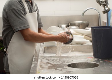 Man Washing Dish On Sink At Restaurant