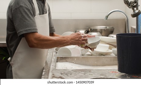 Man washing dish on sink at restaurant - Shutterstock ID 1450907039