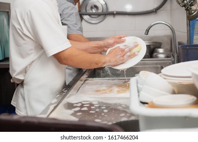 Man Washing Dish On Sink At Restaurant