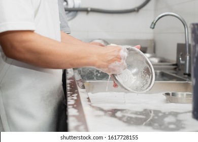 Man Washing Dish On Sink At Restaurant