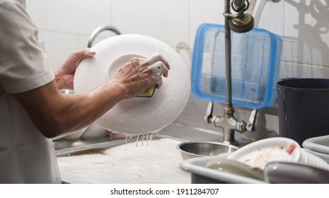 Man Washing Dish On Sink At Restaurant