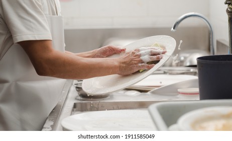 Man washing dish on sink at restaurant - Shutterstock ID 1911585049