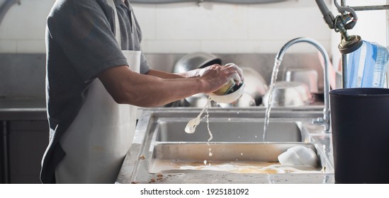 Man washing dish in sink at restaurant.People are washing the dishes too Cleaning solution - Shutterstock ID 1925181092