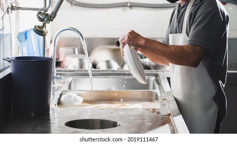 Man Washing Dish In Sink At Restaurant.People Are Washing The Dishes Too Cleaning Solution