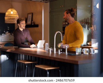 Man washing dishes while boyfriend using digital tablet at home kitchen - Powered by Shutterstock