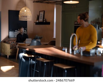 Man washing dishes while boyfriend using digital tablet at home kitchen - Powered by Shutterstock